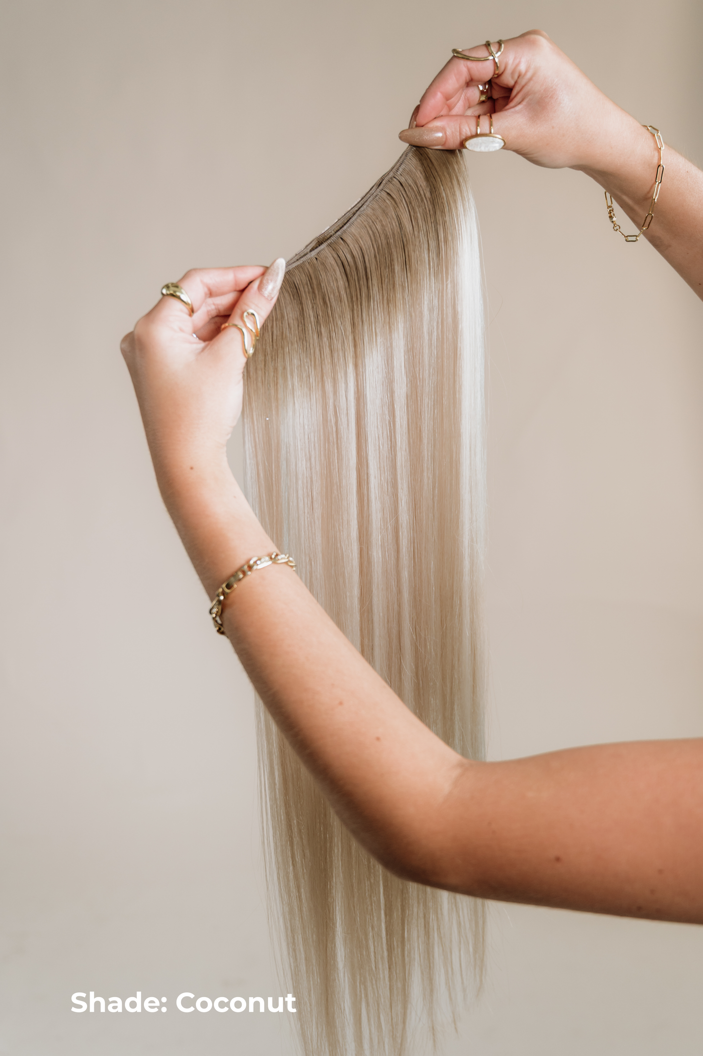Person holding a strand of blonde hair extensions with 'Shade: Coconut' text on a neutral background