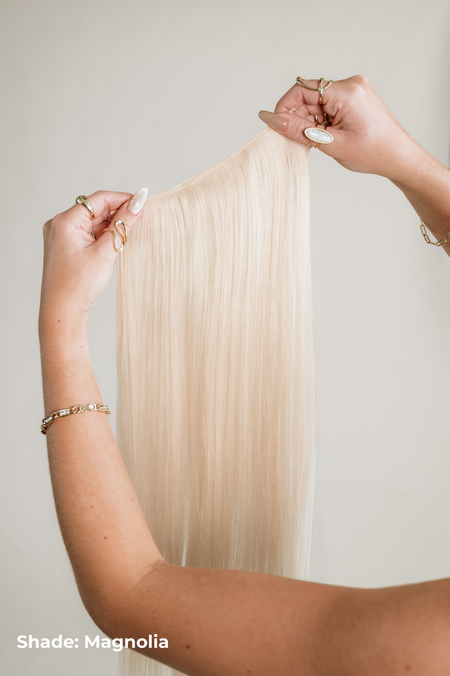 Person holding a long black hair extension against a neutral background