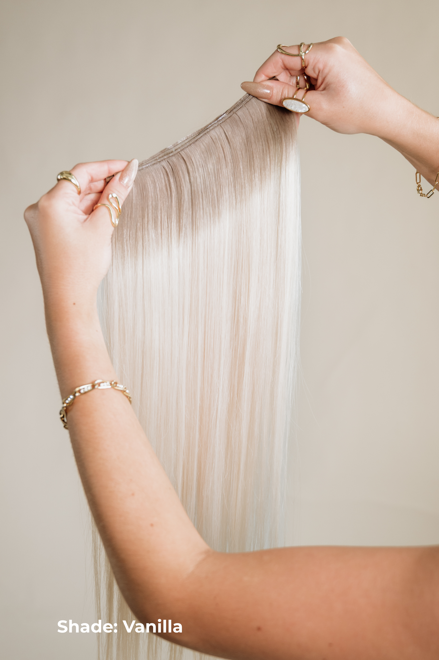 Person holding a strand of blonde hair extensions labeled 'Shade: Vanilla' against a neutral background.